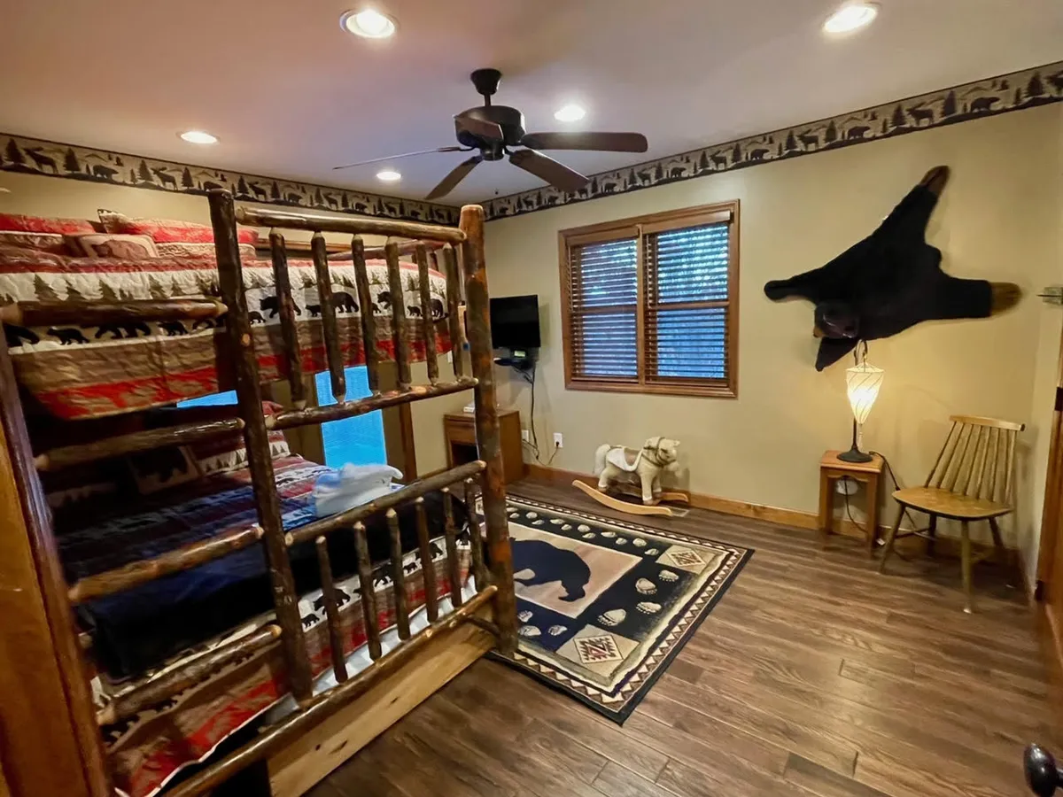 A playful and inviting bunk room featuring natural wood bunk beds, a whimsical bear rug on the floor, and a wooden rocking horse. Soft lighting and wood accents create a cozy atmosphere perfect for both rest and play.