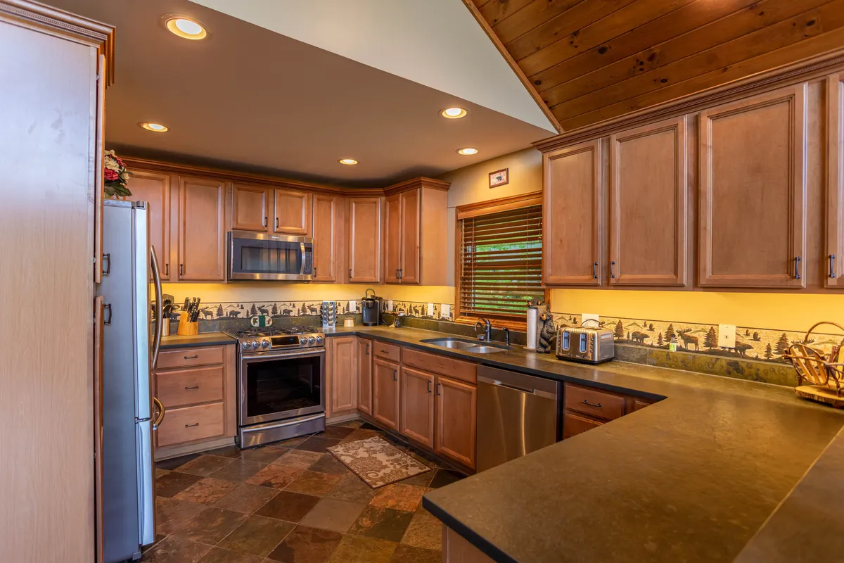 A well-equipped kitchen with a central island, stainless steel appliances, warm wooden cabinetry, and decorative tile accents, offering plenty of space for cooking and socializing.