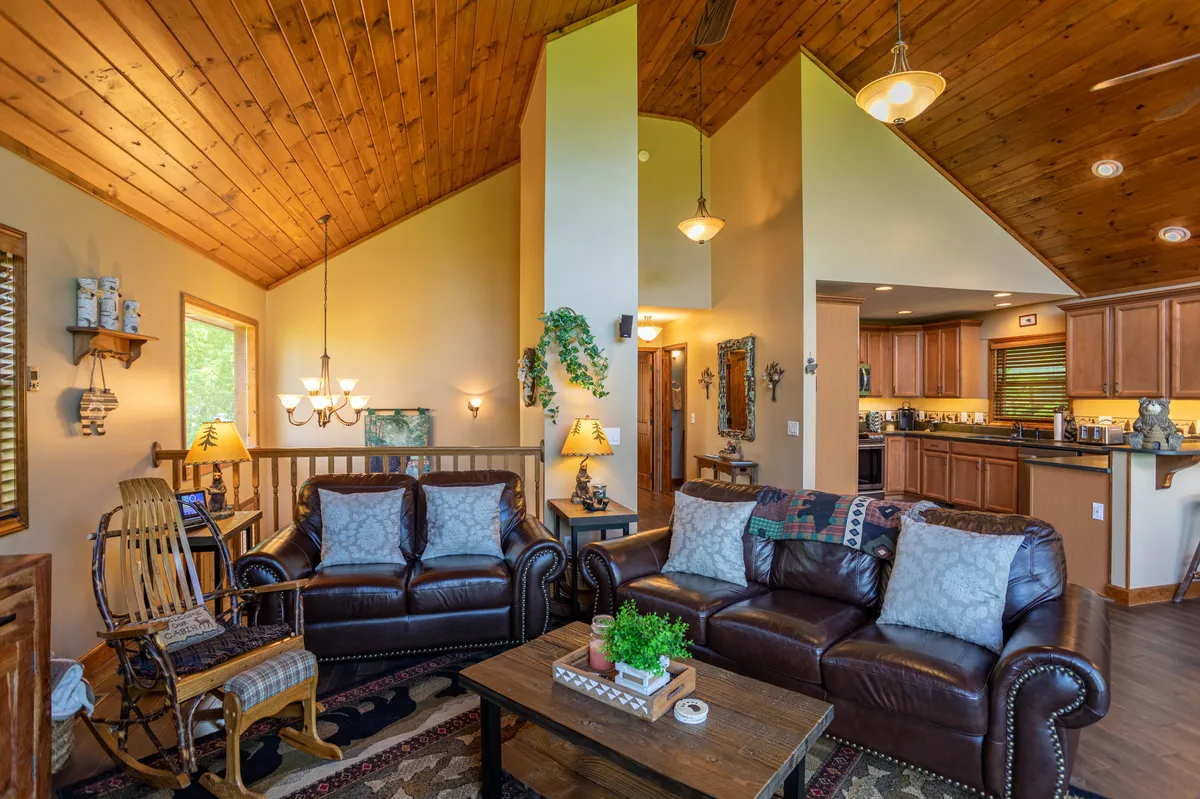 A warm, inviting living room scene centered around plush leather sofas, a sturdy wooden ceiling, and a coffee table suitable for group activities. The space is arranged for family or group gatherings, emphasizing comfort and togetherness.